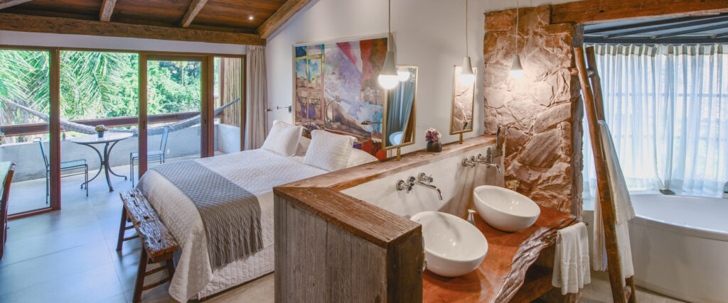 Suíte do Hotel Canto das Águas com obras de arte, ambientes confortáveis e decoração contemporânea em Lençóis, Chapada Diamantina.