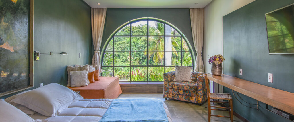 Janela em forma de arco com vista para o jardim de vegetação nativa da Chapada Diamantina no Hotel Canto das Águas.