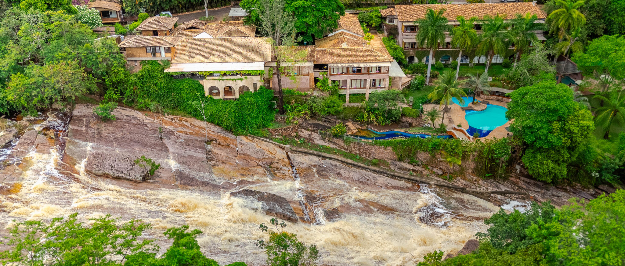 Cachoeiras do Rio Lençóis com o Hotel Canto das Águas ao fundo, em Lençóis, Chapada Diamantina.